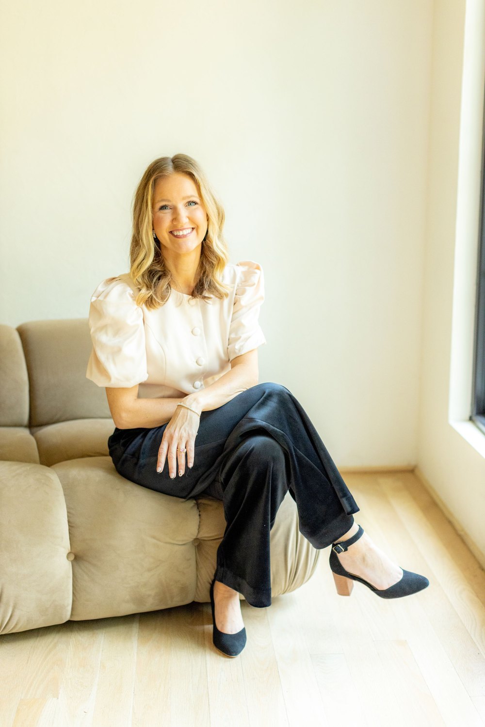 Luann Riley, seated and smiling warmly in a cream blouse